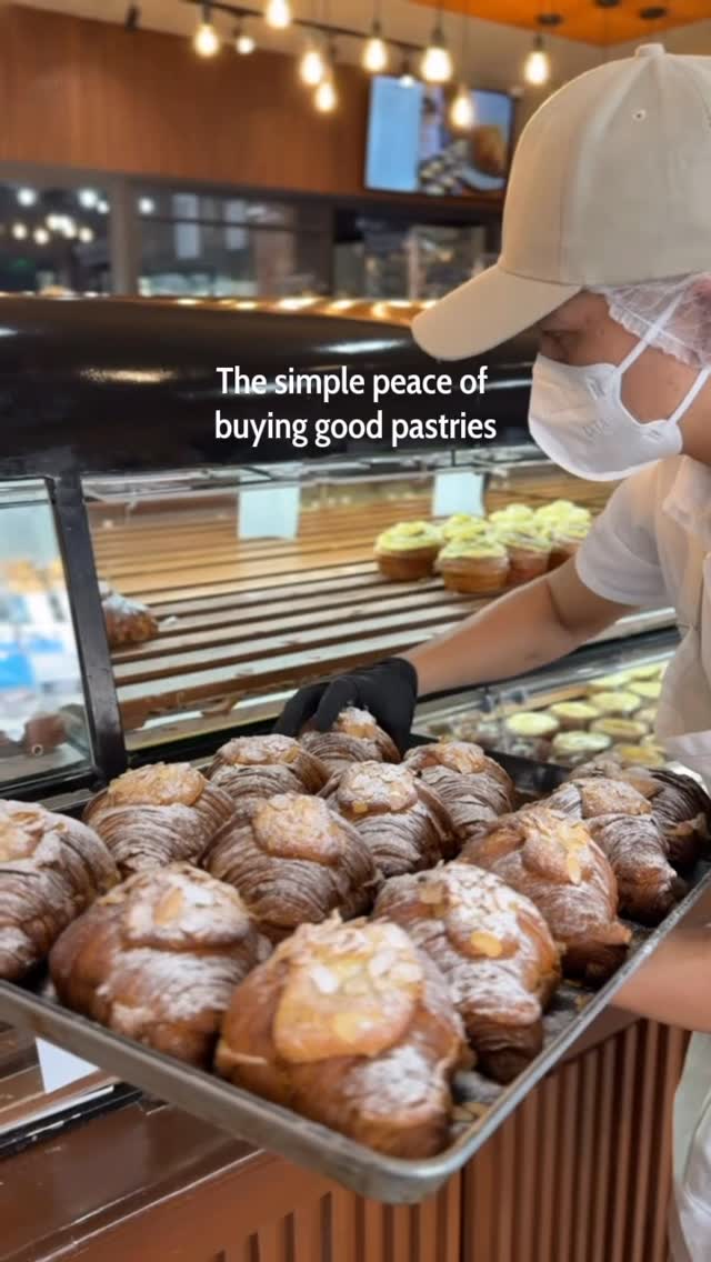 Baker bringing out fresh almond croissants from the oven